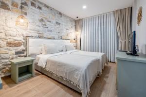 1 dormitorio con 1 cama grande y pared de piedra en Hanedan Hotel Foca Izmir, en Foca
