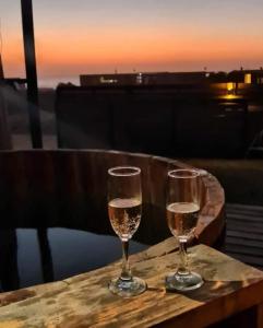 SaldeMar Playa Hermosa في بتشيلمو: كأسين من النبيذ يجلسون على طاولة مع غروب الشمس