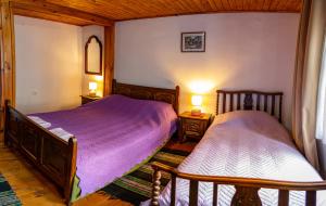 a bedroom with two beds with purple sheets and two lamps at Razsukanova house , Разсукановата къща in Elena