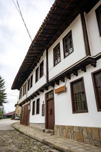 ein weißes Gebäude mit Holztüren und Fenstern in der Unterkunft Razsukanova house , Разсукановата къща in Elena