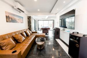 a living room with a brown couch and a kitchen at Turquoise Sichon Pool Villa in Sichon