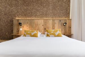 a bedroom with a white bed and a wooden wall at Hôtel Maison Doron in Beaufort