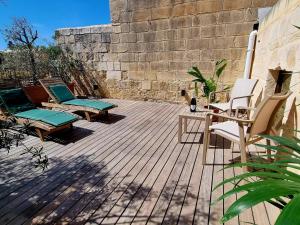 a patio with chairs and tables and a wall at VallettaCharme - 2 bedrooms Flat in the heart of the city in Valletta