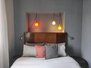 a bed with four pillows and two lights above it at al 28 B&B in Portoferraio