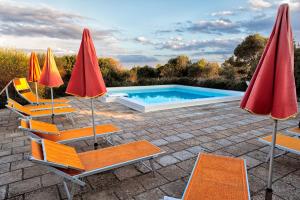 a group of chairs and umbrellas next to a swimming pool at Agriturismo Torre del Cardo in Torre Lapillo