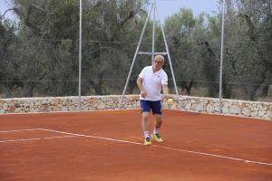 Ein Mann, der einen Tennisball auf einem Tennisplatz hält. in der Unterkunft Agriturismo Torre del Cardo in Torre Lapillo