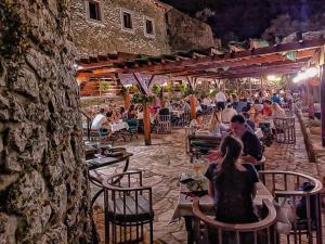 personnes assises à table dans un restaurant en plein air la nuit dans l'établissement Hotel Restoran Humsko, à Trebinje