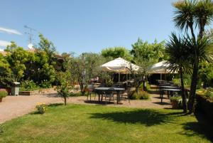 un patio con tavoli e ombrelloni in giardino di Locanda Da Vittorio a Manerba del Garda