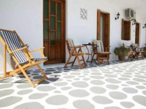 a patio with rocking chairs and a table in a house at Andreas and Petrinela Rooms in Triovasálos +10 photos