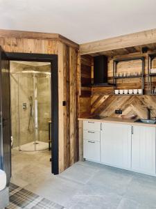 a bathroom with a shower and a kitchen with wooden walls at Willa Arkady in Zakopane
