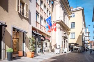 um edifício com bandeiras ao lado de uma rua em Hotel San Carlo em Lugano