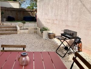 a picnic table and a grill in a backyard at L’Oustau de Célia in Maussane-les-Alpilles