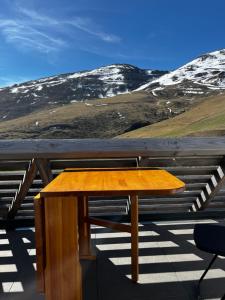 una mesa de madera en la parte superior de un techo con montañas cubiertas de nieve en Ski Piau Engaly, plein sud avec vue sur les pistes à 50 m, cœur de station, en Aragnouet