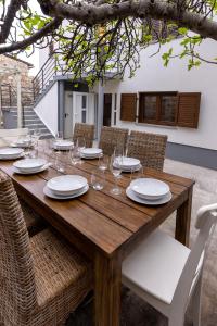 a wooden table with white plates and wine glasses at Casa Bella in Karlobag