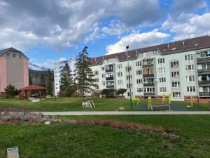 ein großes weißes Gebäude mit einem Spielplatz in einem Park in der Unterkunft Ubytovanie pod štítmi Vysokých Tatier in Tatranska Strba