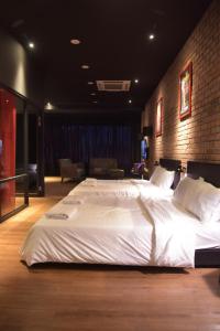 uma cama grande num quarto com uma parede de tijolos em The Label Suites Ipoh em Ipoh