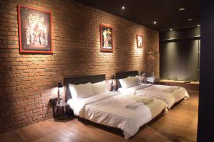 twee bedden in een kamer met een bakstenen muur bij The Label Suites Ipoh in Ipoh