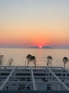 een zonsondergang boven het water met bomen op de voorgrond bij Sunset Resort in Vlorë