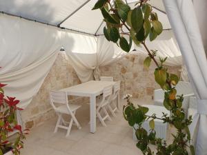 une table et des chaises blanches dans une tente dans l'établissement Mamapulia Home, à Alberobello