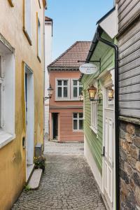 a narrow alley with a green and white building at Bryggen Living in Bergen