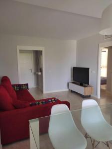a living room with a red couch and white chairs at Apartamento bonito - playas las Deveses in El Verger