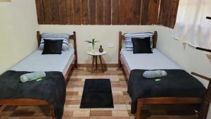 two twin beds in a room with a table at Chalé Recanto da Cachoeira I in Eldorado