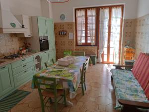 a kitchen with green cabinets and a table with chairs at Brezza Marina & L'oasi Blu in Castelsardo