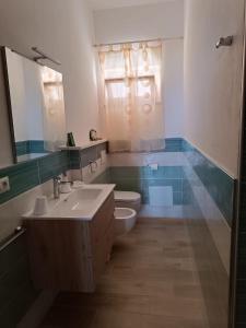 a bathroom with a sink and a toilet and a mirror at Brezza Marina in Castelsardo