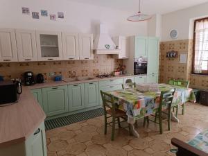 a kitchen with green cabinets and a table with chairs at Brezza Marina & L'oasi Blu in Castelsardo +43 photos