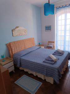 - une chambre avec un lit doté de draps bleus et une fenêtre dans l'établissement Brezza Marina IUN R6124, à Castelsardo