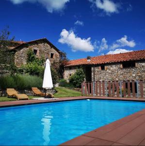 a swimming pool with a umbrella next to a building at Agriturismo Cilla in Giuncugnano