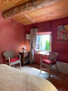 1 dormitorio con 2 sillas, mesa y ventana en Le petit Mas, en Vogüé