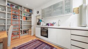 cocina con armarios blancos, mesa y fregadero en Central Chelsea 1 Bedroom, en Londres