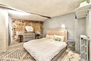 1 dormitorio con cama y pared de piedra en TOWNHOUSE MOUGINS in the old village, fantastic view, sea and mountains, en Mougins