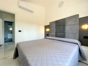 una camera da letto con un letto grande con testiera grigia di Villa Wanda a Bibione