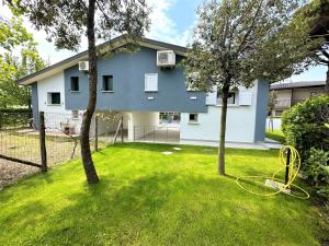 una casa blu con due alberi in un cortile di Villa Wanda a Bibione