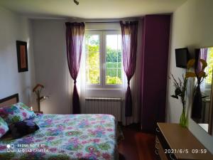 een slaapkamer met een bed en een raam met paarse gordijnen bij El naranjo in Gama
