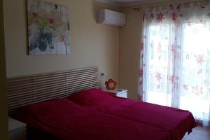 um quarto com uma cama vermelha e uma janela em Casa Olga em Benissa