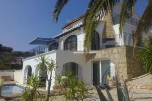 uma casa branca com palmeiras e uma piscina em Casa Olga em Benissa