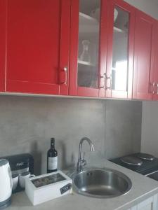 encimera de cocina con fregadero y armarios rojos en Anna's Cottage Home en Galini