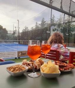 een tafel met twee glazen wijn en eten op een tennisbaan bij Camper Village in Santo Stefano al Mare