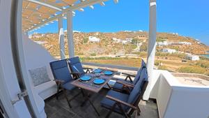 patio con mesa y sillas en el balcón en 1Path Pelican Mykonos Super Paradise Beach House, en Mykonos ciudad