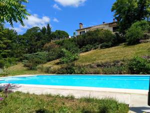 a blue swimming pool in front of a house at Maison Les Fraysses in Bellefont-La Rauze