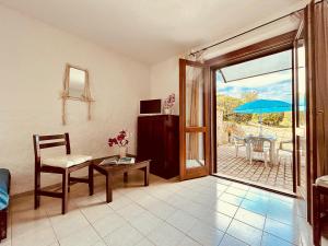 sala de estar con silla y mesa con sombrilla en Casette Belvedere, en Baja Sardinia