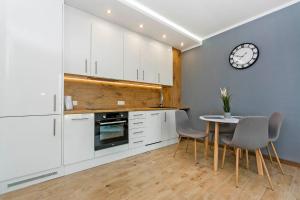 uma cozinha com armários brancos e uma mesa e cadeiras em Apartament Baltic Sea 3 - Gdańsk Przymorze em Gdansk