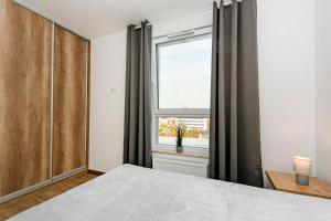 um quarto com uma cama grande e uma janela em Apartament Baltic Sea 3 - Gdańsk Przymorze em Gdansk