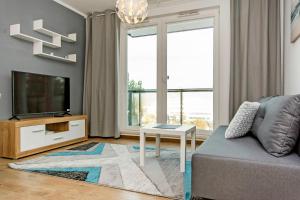 uma sala de estar com um sofá e uma televisão em Apartament Baltic Sea 3 - Gdańsk Przymorze em Gdansk