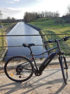 a bike parked on a bridge next to a river at Les volets bleus in Charlieu