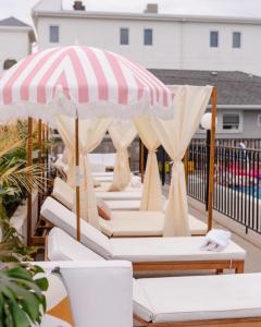 a row of white beds on a patio with an umbrella at The Shore House in Wildwood