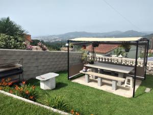 um jardim com um banco e um gazebo em Casa de vacaciones em Baiona